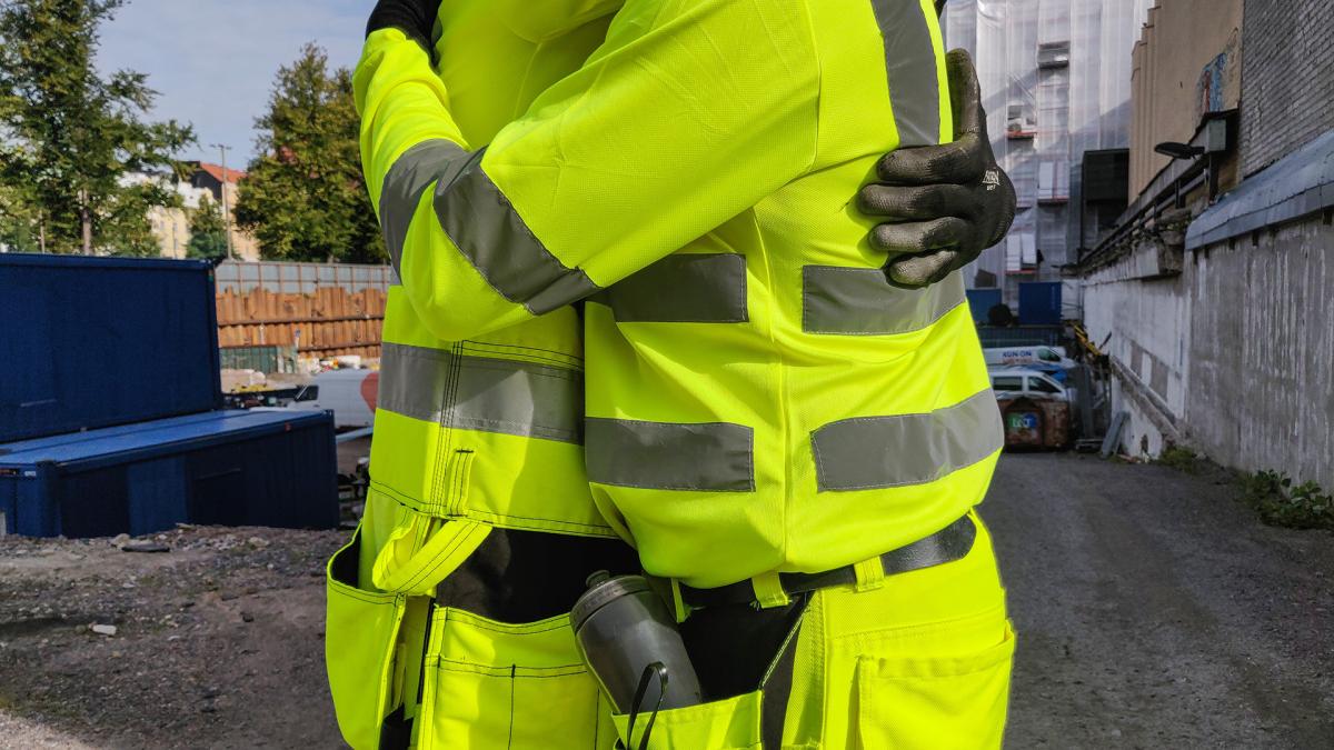 Kuvassa kaksi neonkeltaisiin asuihin pukeutunutta henkilöä halaa toisiaan.