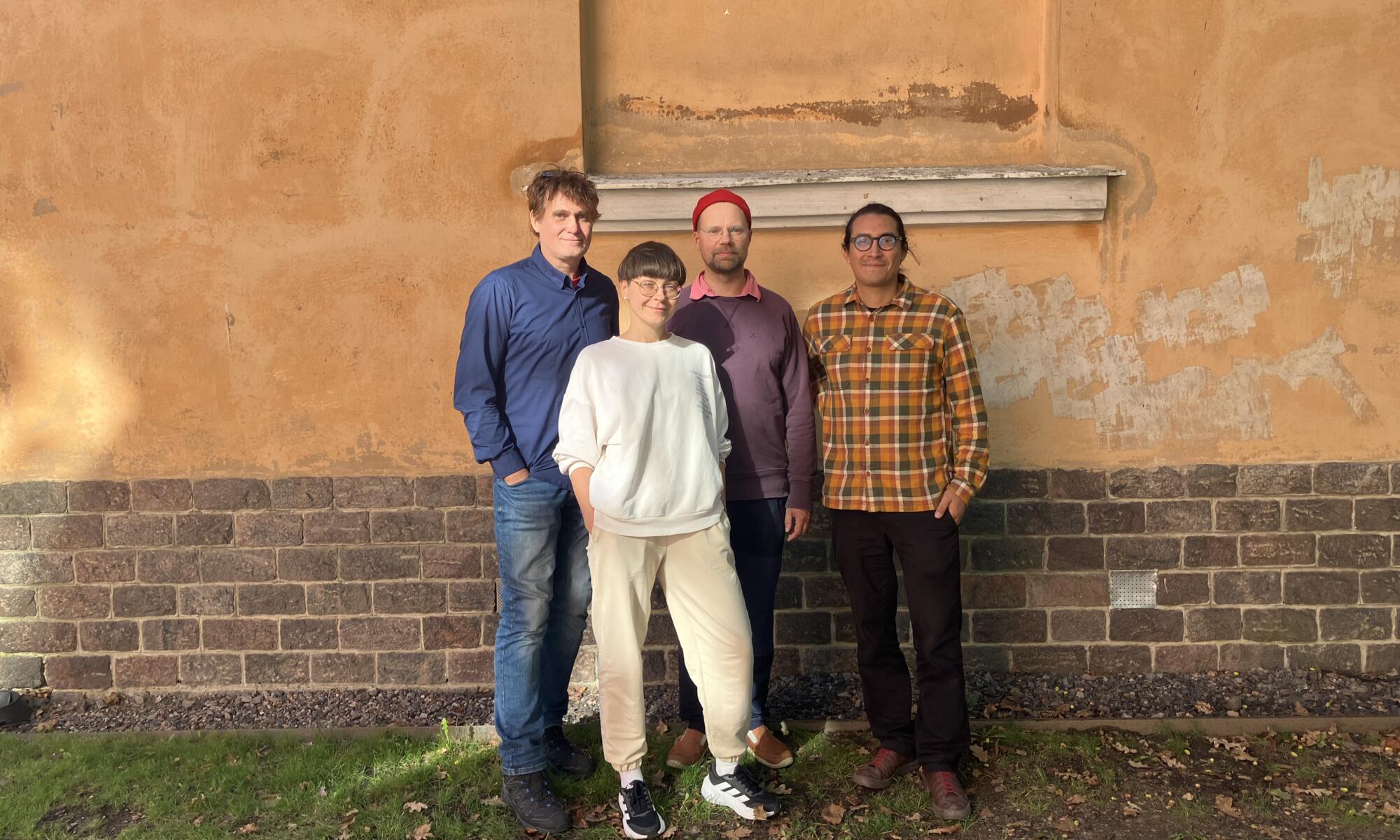 The four ExoSound researchers stand in front of a yellow building in relaxed clothes.
