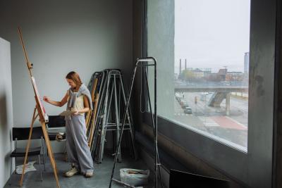 Kuvituskuva opiskelijasta Kuvataideakatemian tiloissa maalaamassa taulua.