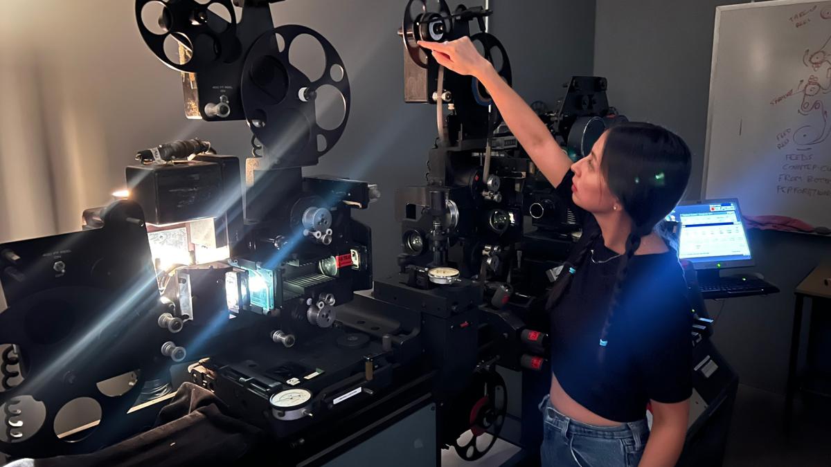 Paola Guzmán Figeroa pointing at an Oxberry 1600 optical printer.