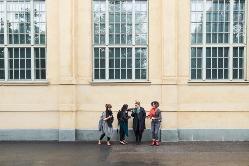 Four women standing in front of a yellow facade