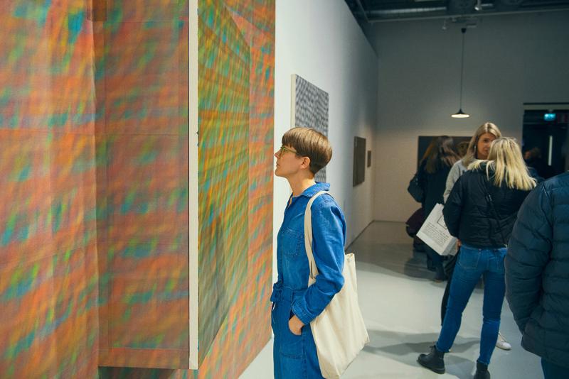 Henkilö katsoo teosta taidenäyttelyssä. Kuva: Veikko Kähkönen