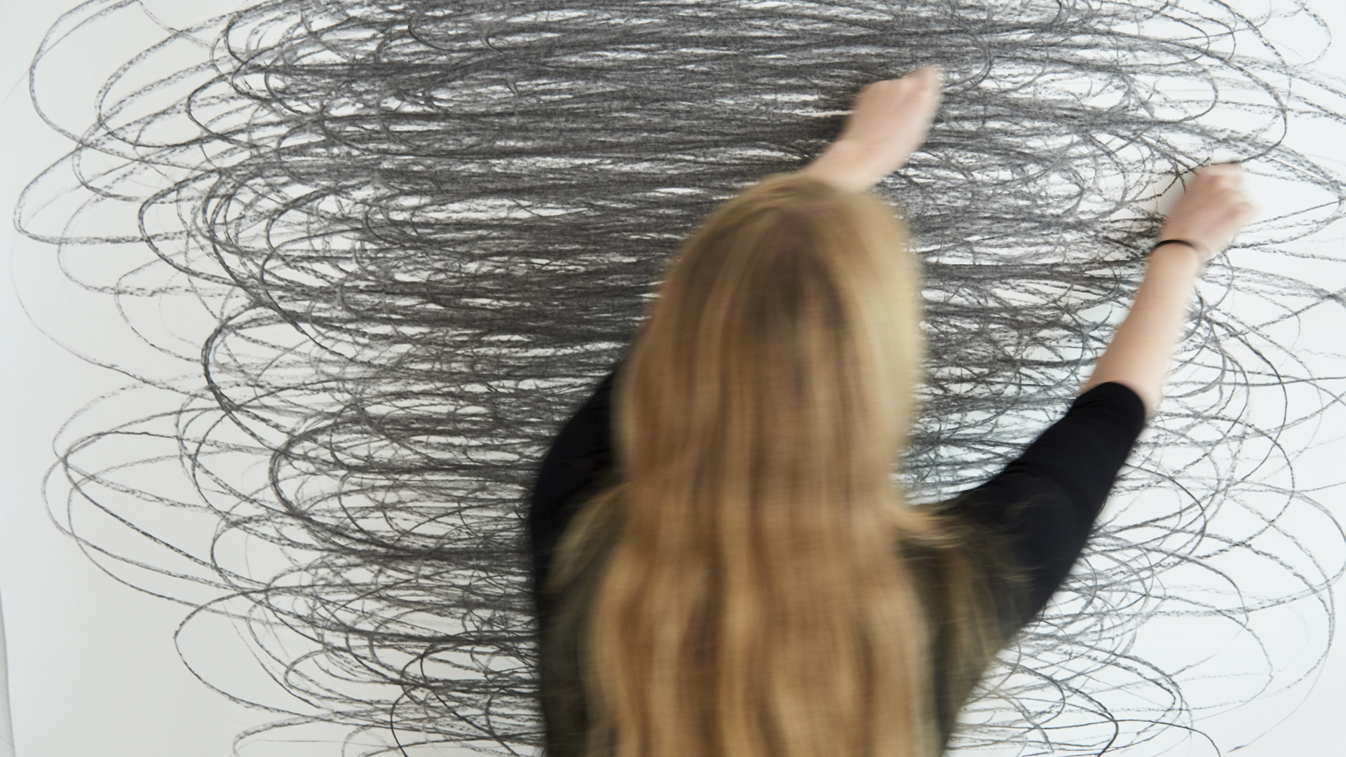 A student making a drawing on a white surface.