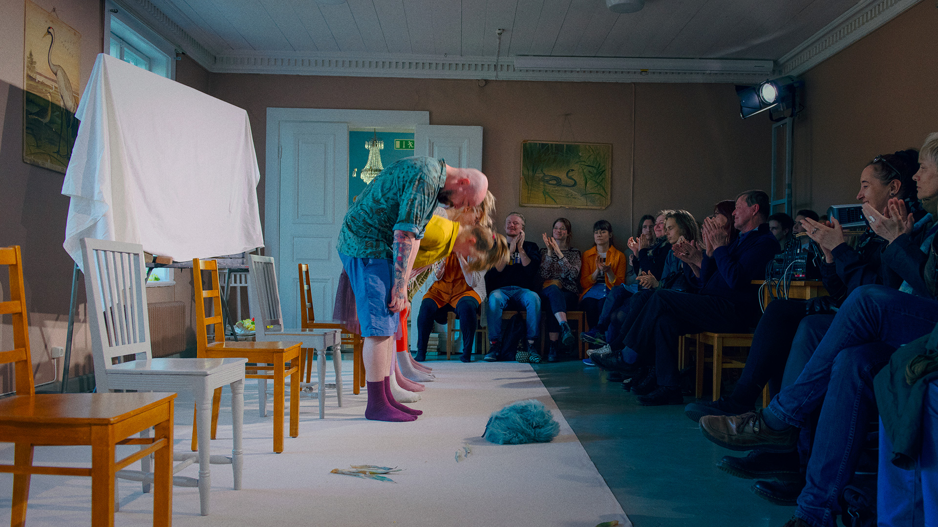 Actors bowing for the audience in a large room.