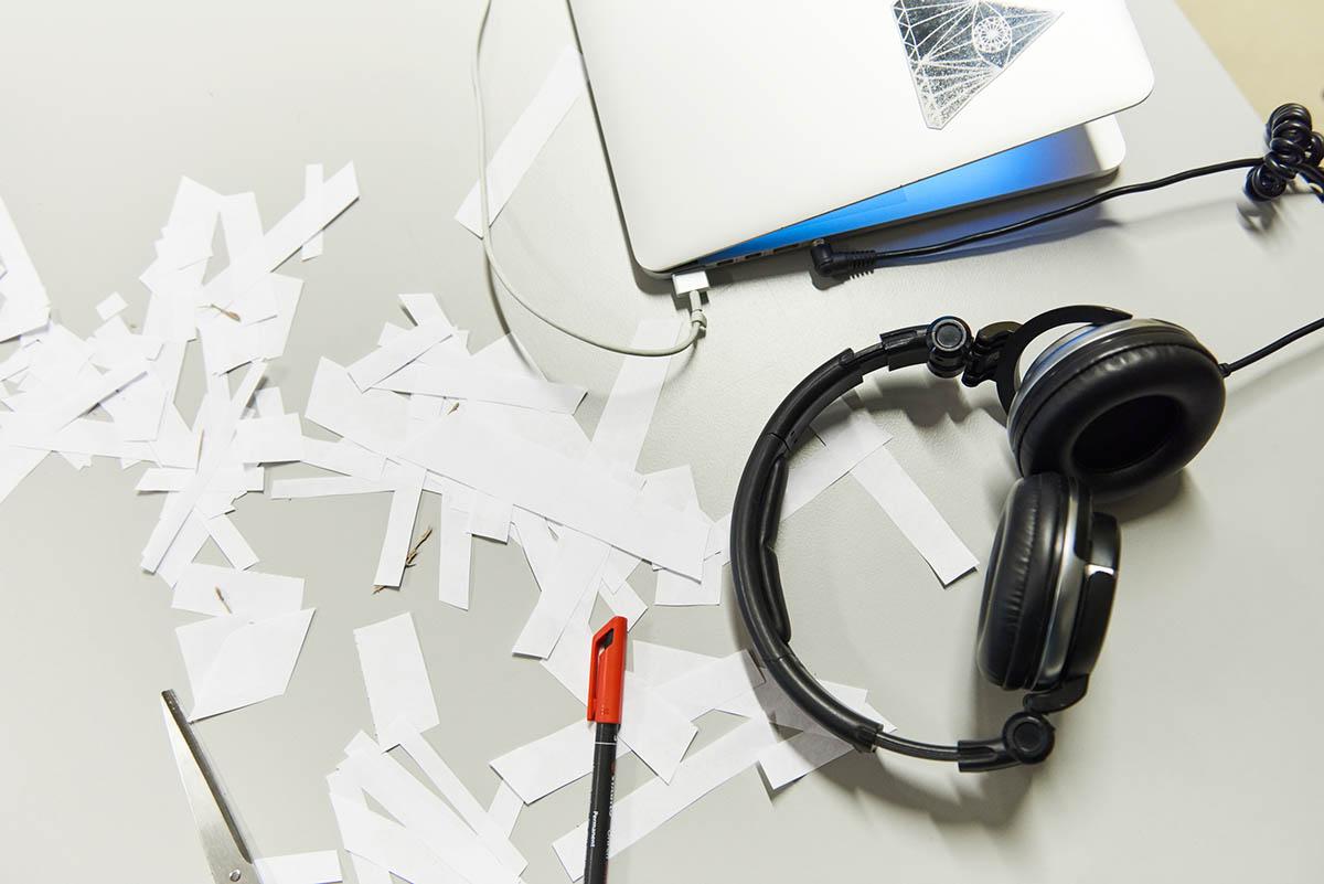 Laptop, pieces of paper and headphones on a table