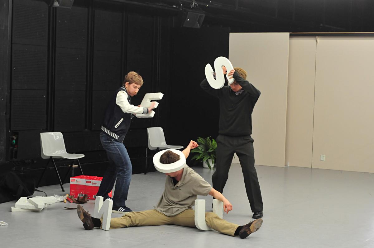 Performers playing with alphabet objects on stage.