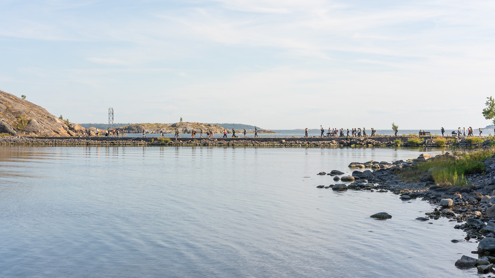 From a distance, people crossing a neck of land that connects Vallisaari and Kuninkaansaari islands.