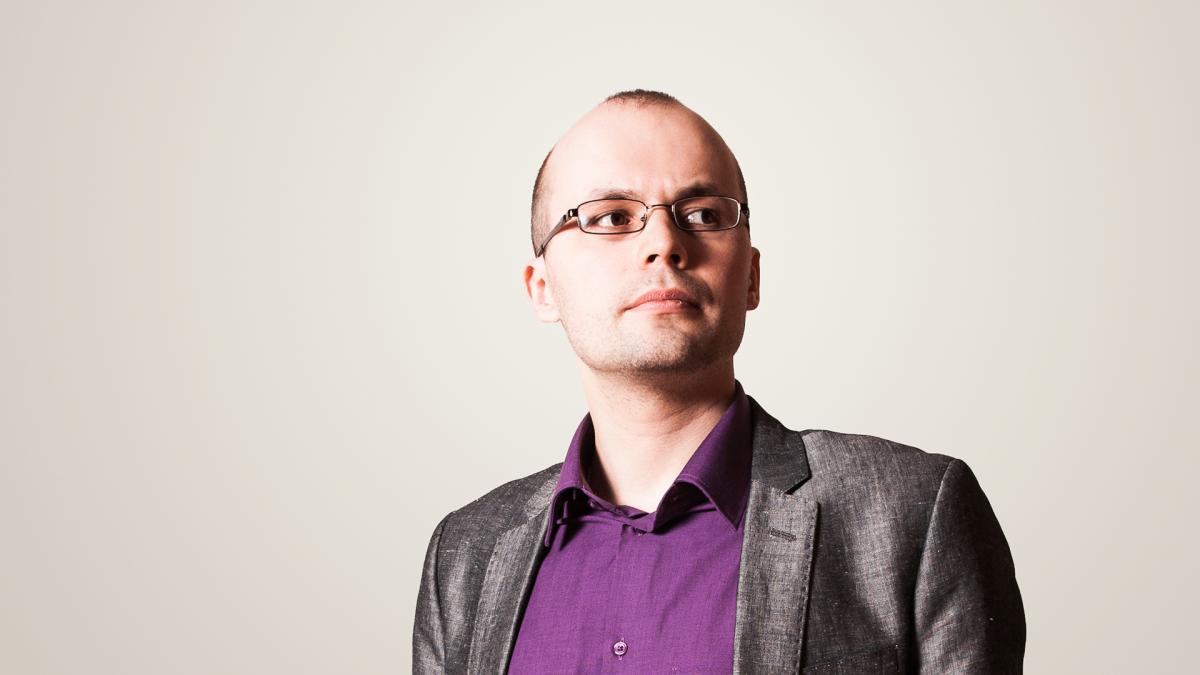Kirill Kozlovsky poseeraa valkoista taustaa vasten ja katsoo oikealle kameran ohi.