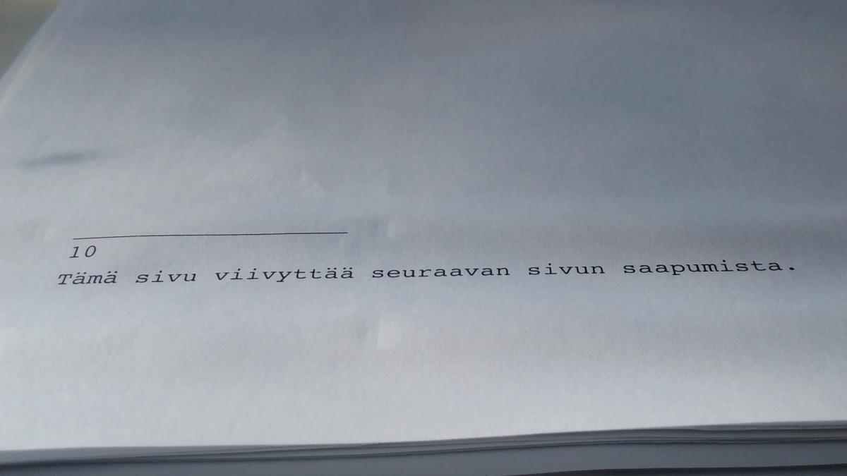 Kuvassa valkoinen paperi, jonka alareunassa tekstiä.