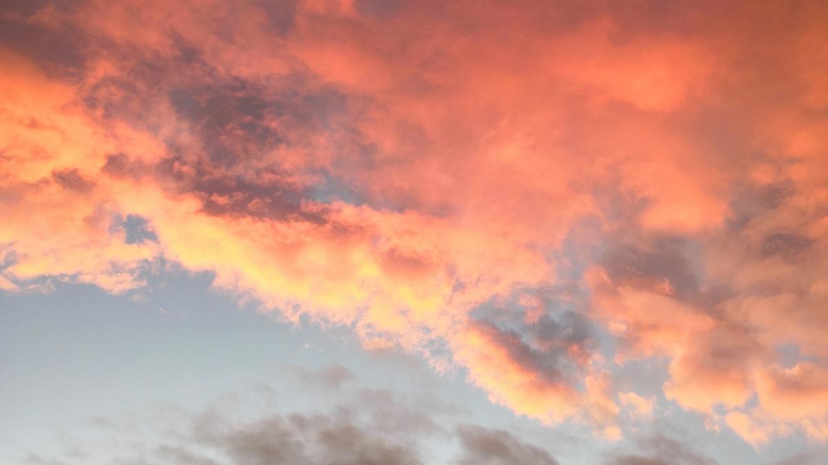 Kuva otettu auringonlaskun aikaan. Kuvassa näkyy vähän sinistä taivasta ja punaisia pilviä.