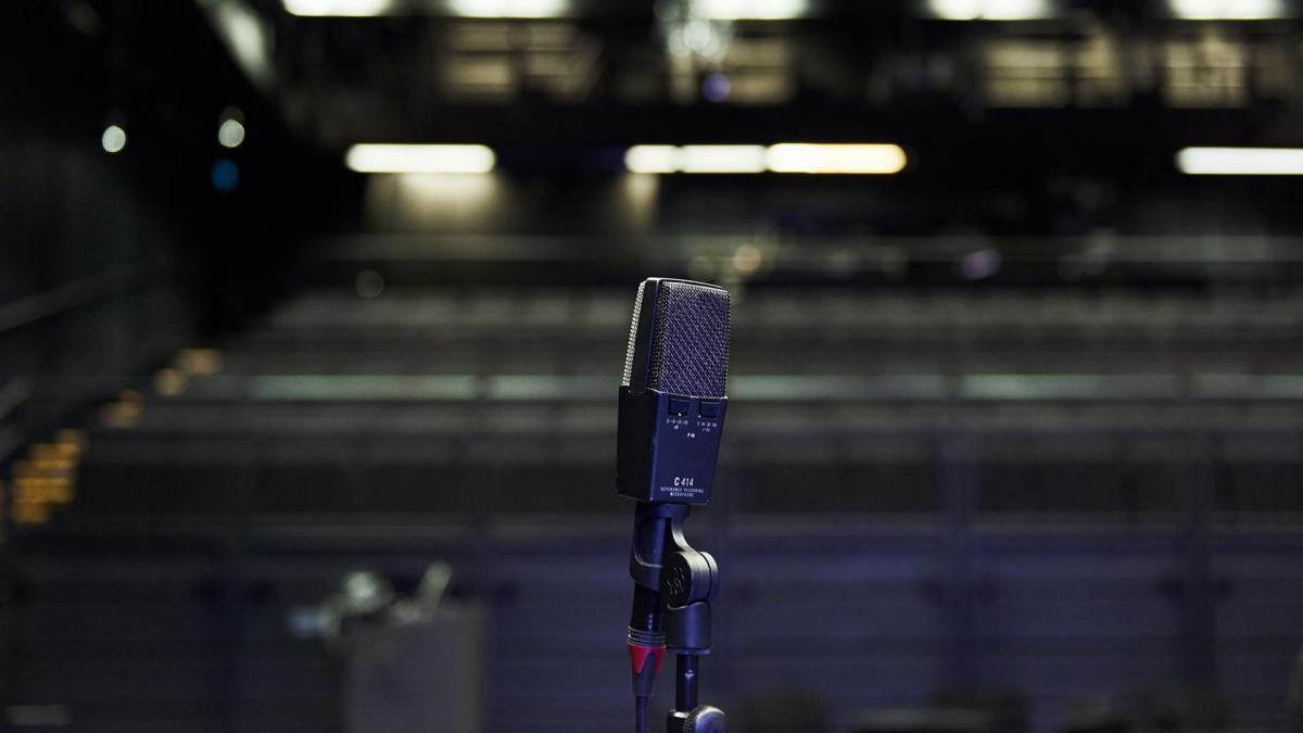 A microphone photographed in front of an empty audience. The image is dark.