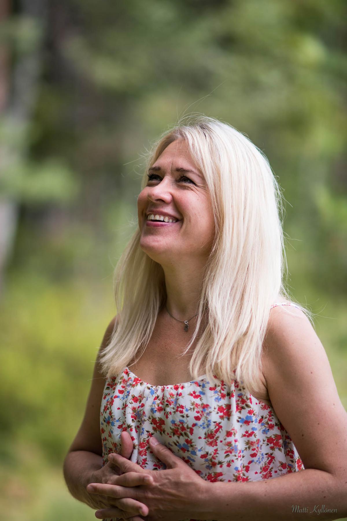 Heini Kärkkäinen smiles and looks up on this picture. She has crossed her hands against her chest.