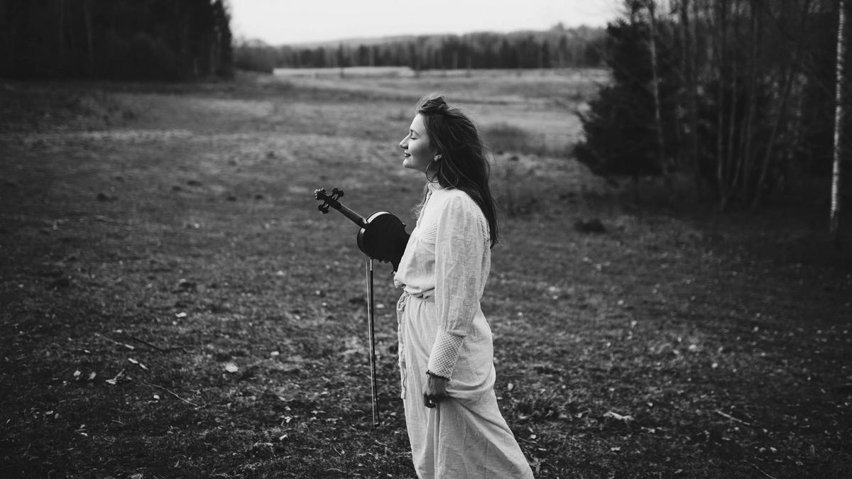 Kärt Tambet stands in the field eyes closed with a little smile on her face.