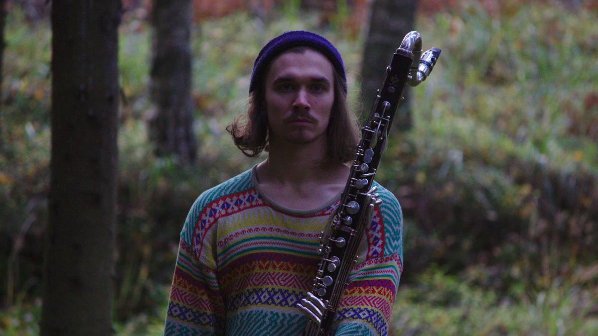 Jaakko Arola in a forest wiith a wood instrument