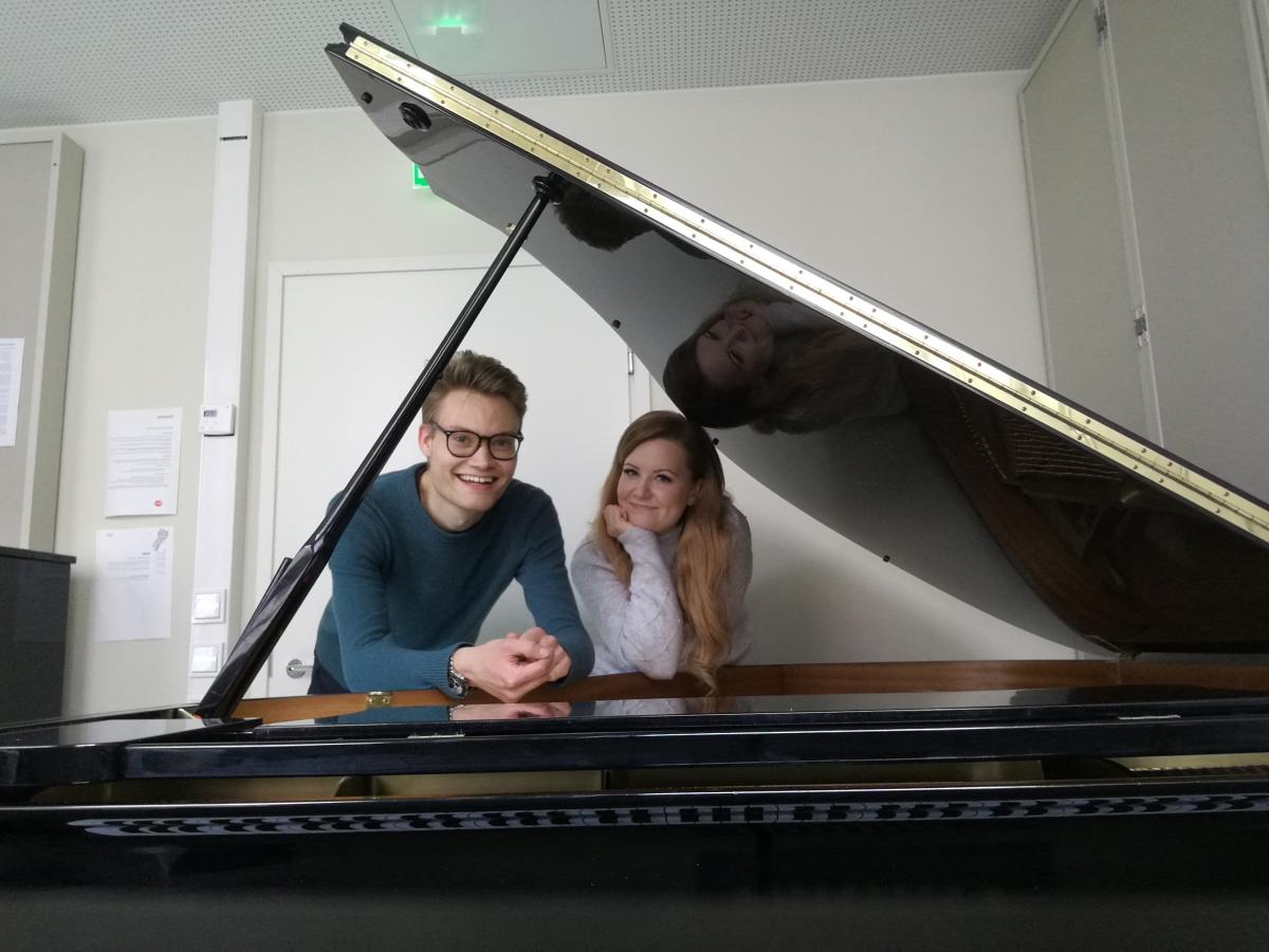 Young man and a young woman behind a piano