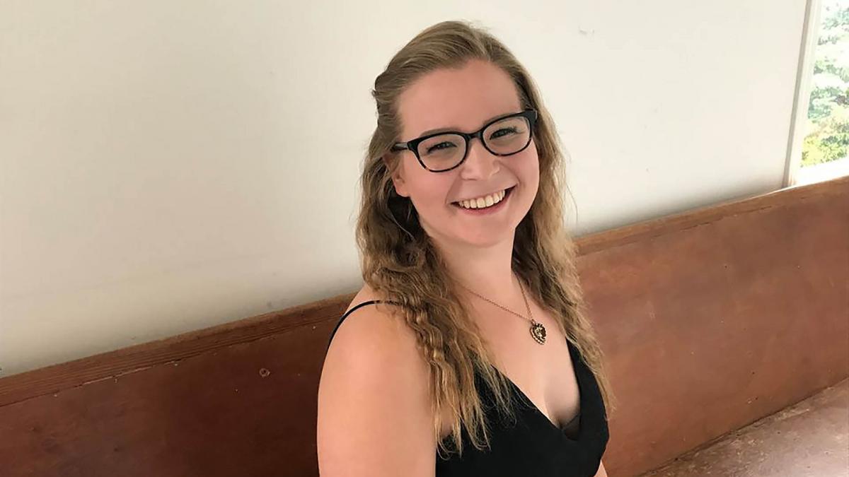 Lili Ahopelto sitting on a church bench and smiles for the camera