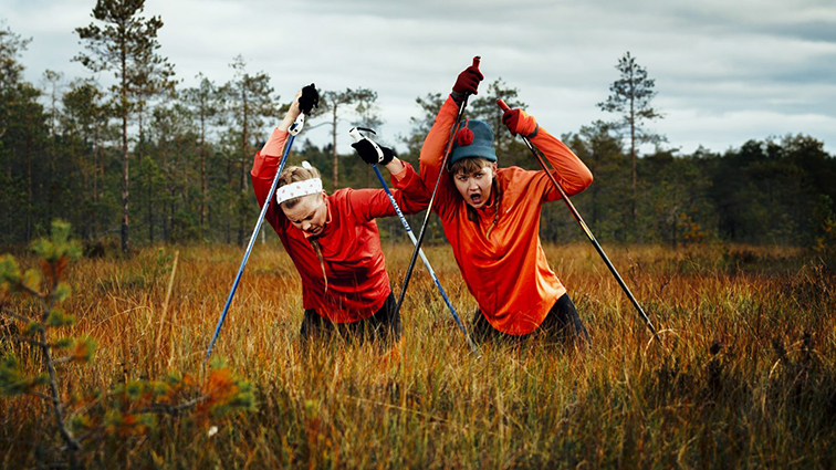 Kaksi henkilöä suolla suksisauvat käsissään.