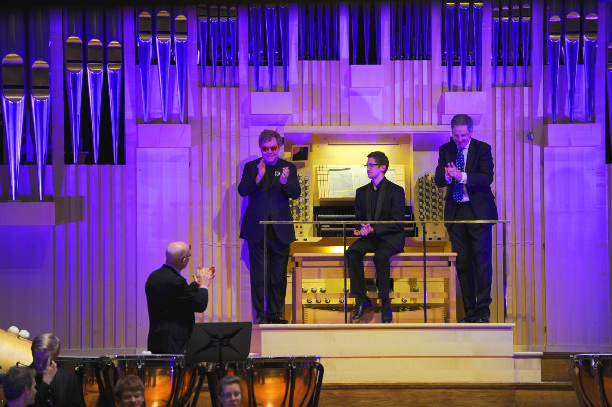 Three men in front of an organ