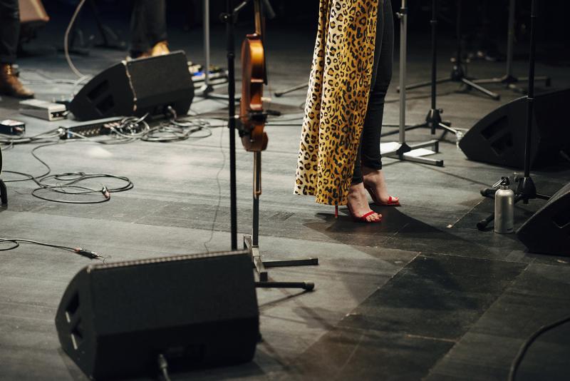Person's feet in high heels on a stage with technical equipment.