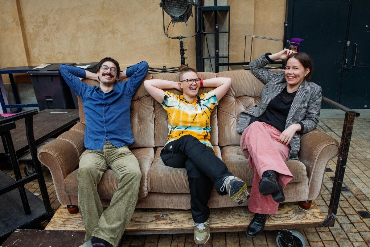 Three people sitting on a coach