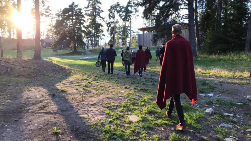 People walking away from the camera on a summer evening at a wooded area, sun is setting in the background.