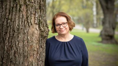 Marjo Kaartinen nojaa puuhun puistossa
