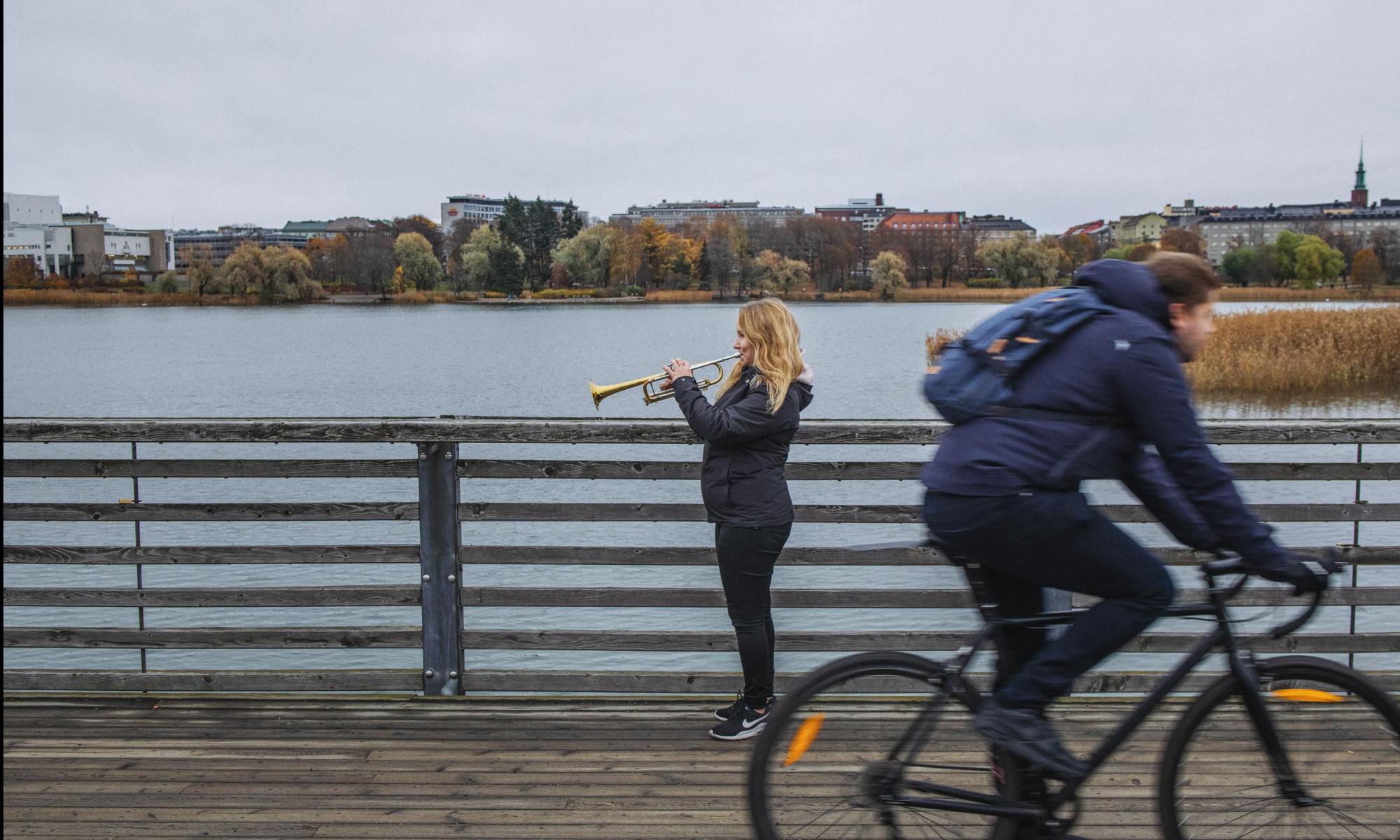 Torvensoittaja Töölönlahdella, pyöräilijä etualalla.