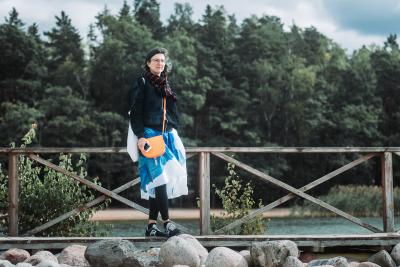 A photo of Taru Elfving on a dock with green trees at the background and some rocks on the foreground.