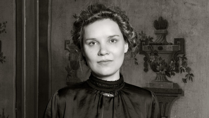 Mustavalkoinen kuva tutkija Nuppu Koivistosta pukeutuneena 1800-luvun asuun.