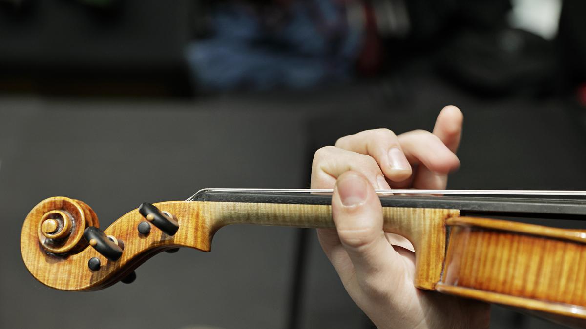 Käsi on viulun kaulalla. Kuva on otettu, kun viulua on soitettu.