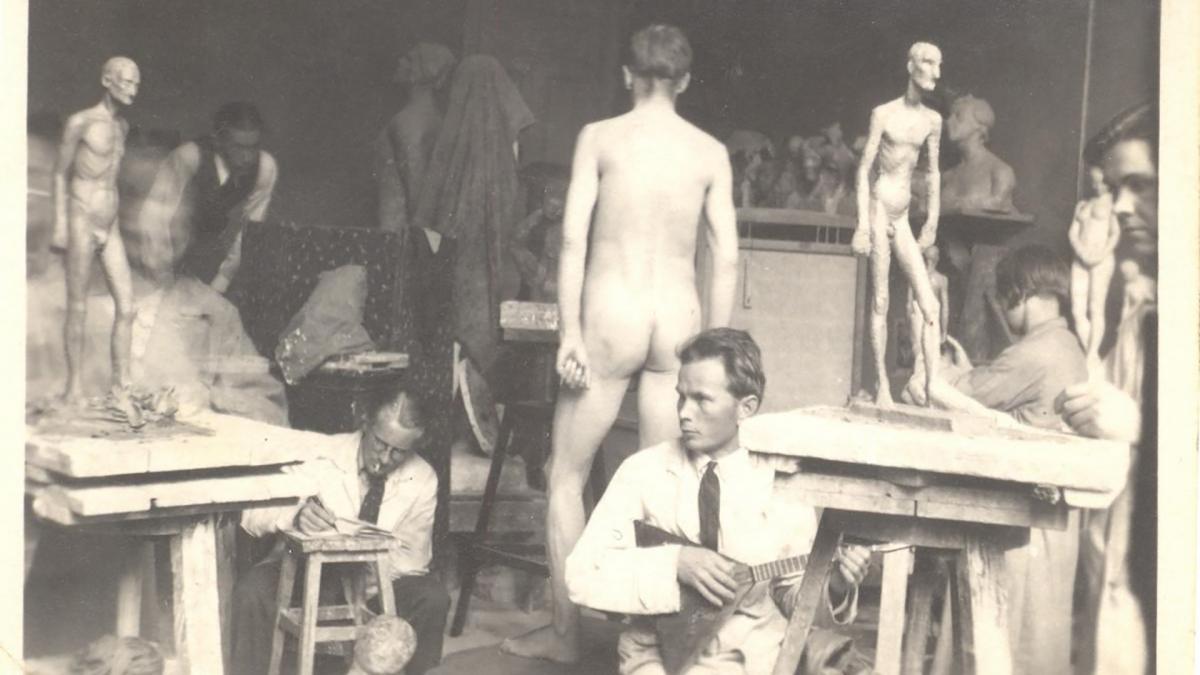 Kuvanveistoluokka, jossa on opiskelijoita veistämässä, sekä huoneen keskellä alaston miesmalli.